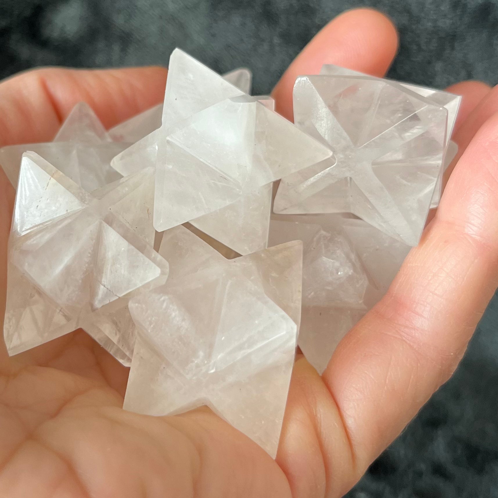 Large quartz merkaba stones, radiant with crystalline energy, ideal for meditation and spiritual practices held gently in the palm of a hand.