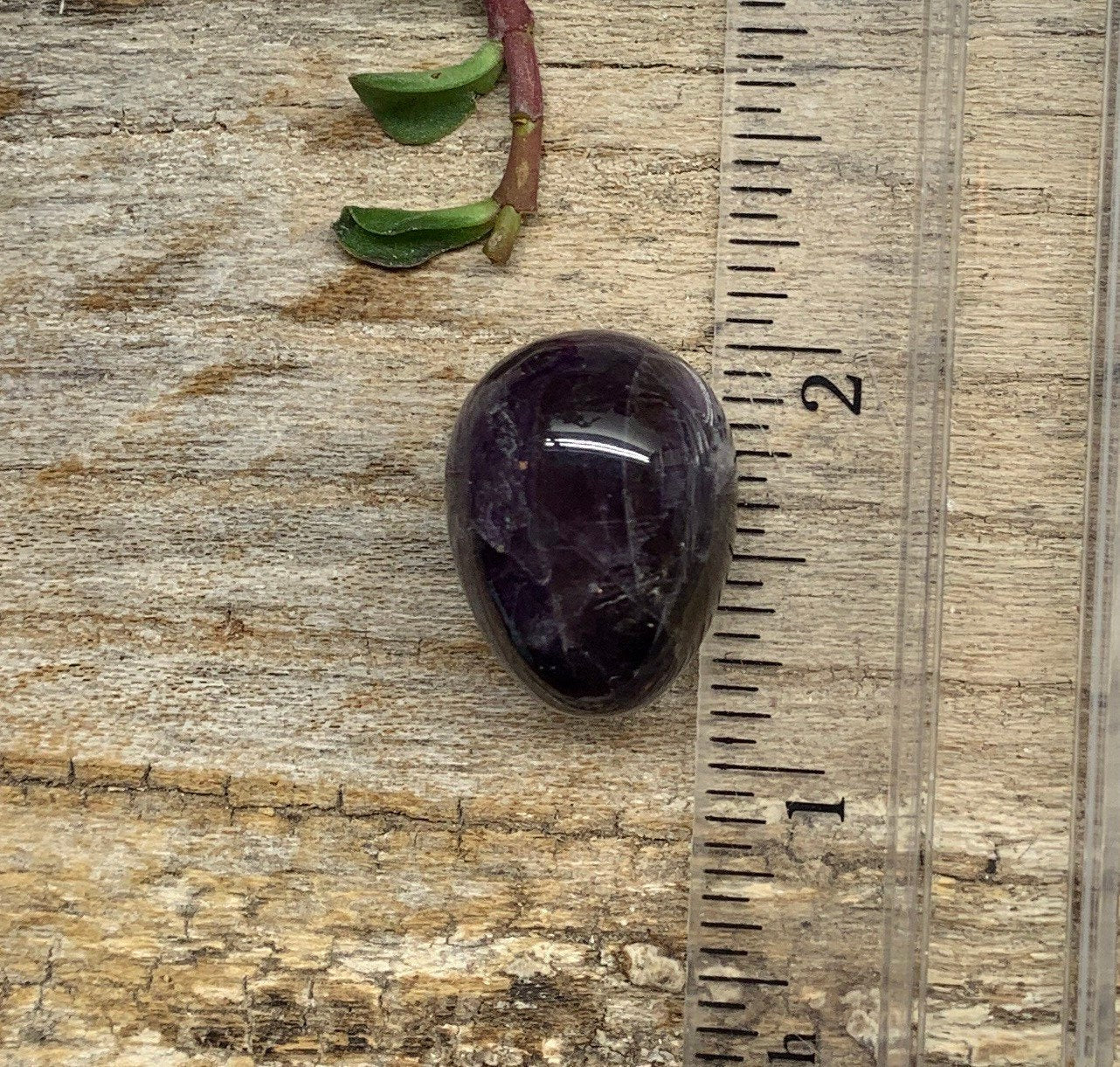 Shimmering purple amethyst egg with intricate patterns and a sense of mystique, displayed next to a ruler.  egg is approximately 3/4"