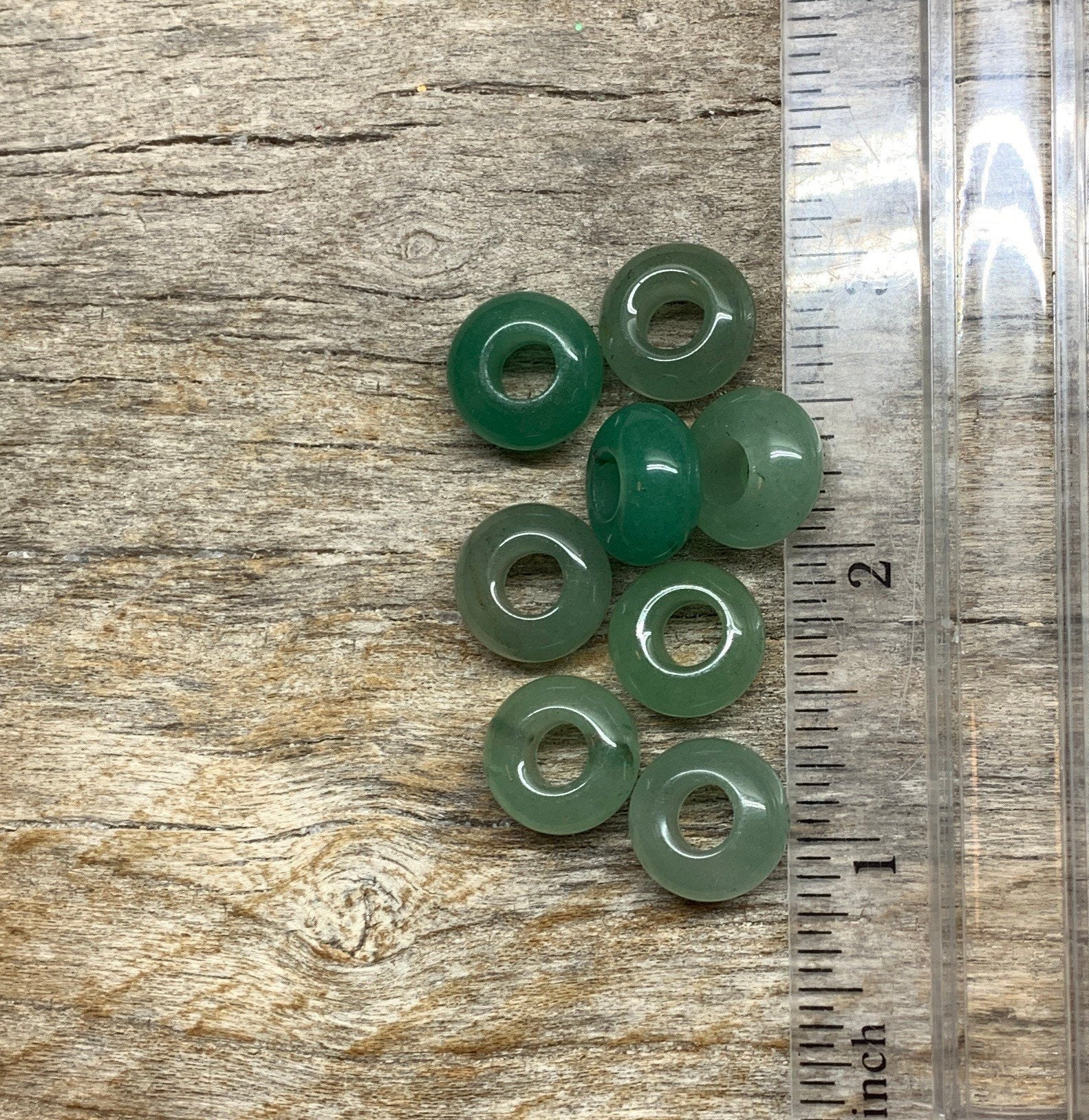 "Close-up of 14mm round green Aventurine beads, showing their smooth surface and rich color, positioned next to a ruler