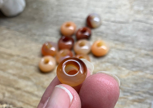 "Close-up view of 14mm carnelian agate beads, showcasing their vibrant orange hues and smooth, polished surfaces.