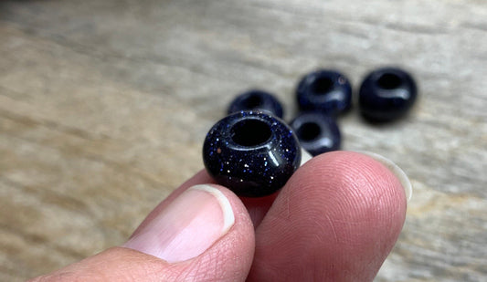 Blue goldstone beads, each measuring 14 mm in diameter. The beads exhibit a deep blue color with sparkling metallic flecks, creating a captivating and shimmering appearance.