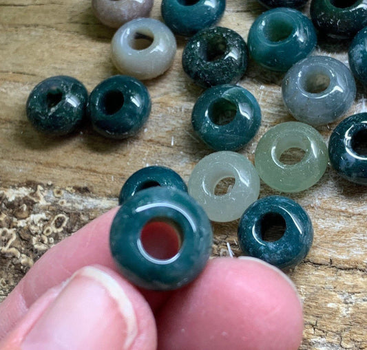 "Close-up view of lustrous moss agate beads, showcasing intricate green and brown patterns.
