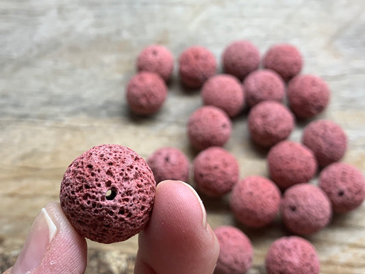 "Close-up of round pink lava beads, showcasing their textured surface and vibrant color.