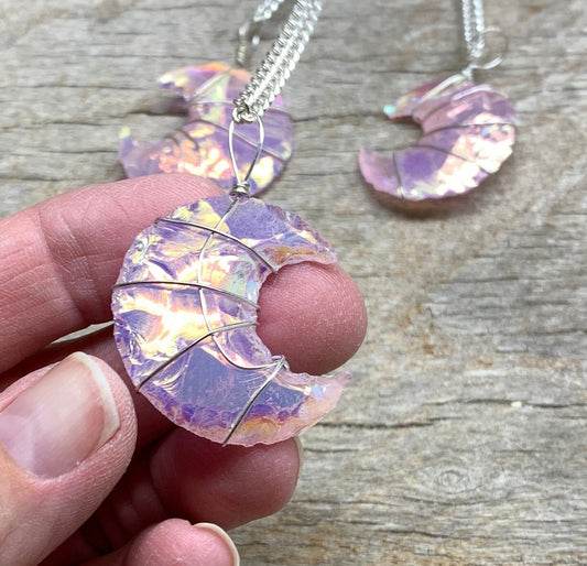shimmery mettallic lookong ponk angel aura pink opalite, knappes creacent moon ornately silver wire wrapped pendant attatched to a silver chain.