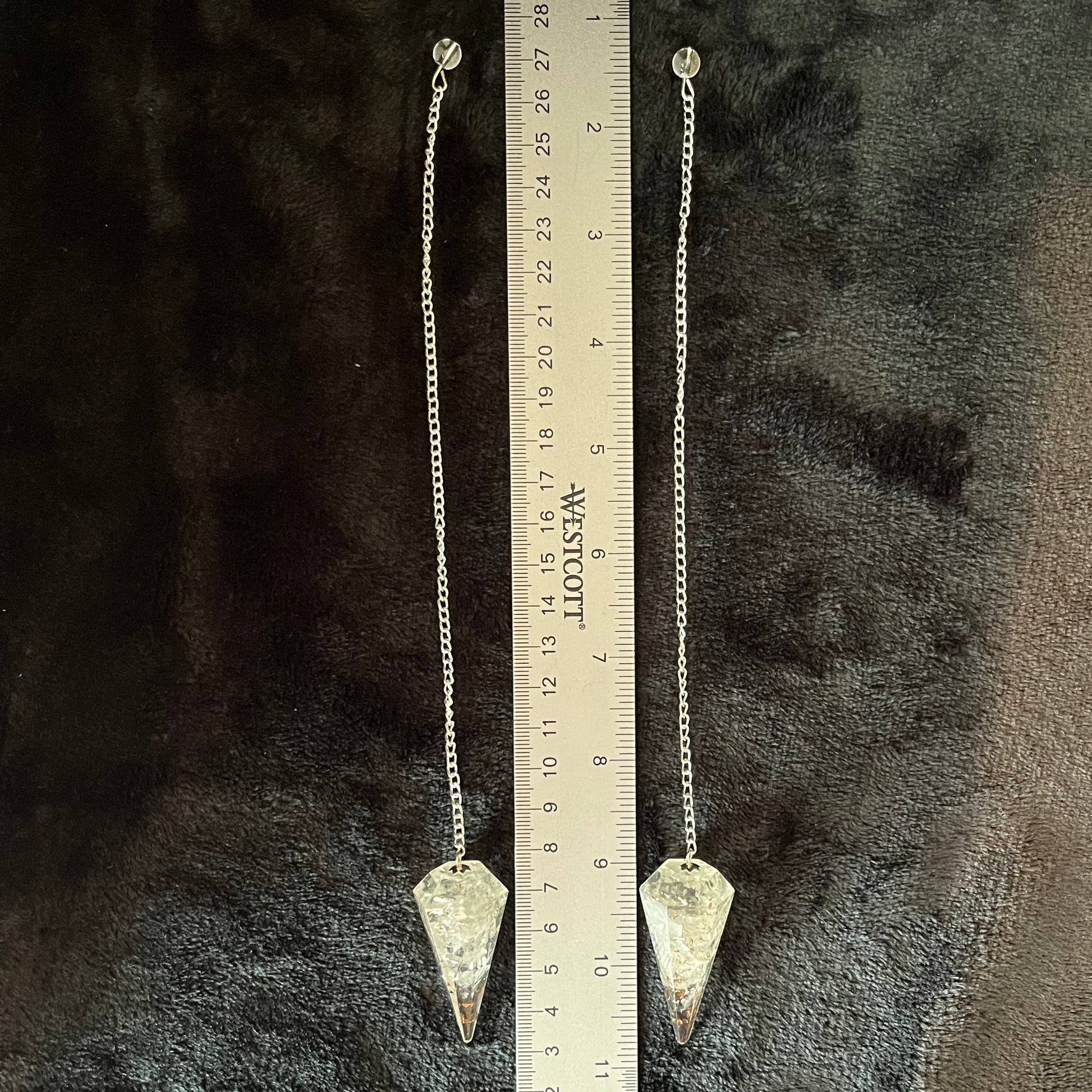 2 Quartz organite pendulums featuring a clear quartz crystal suspended in resin, designed for divination and energy work, displayed next to a ruler.  Quartz oraganite crystal point is approximately  1 3/4” long attatched to an 8” chain.
