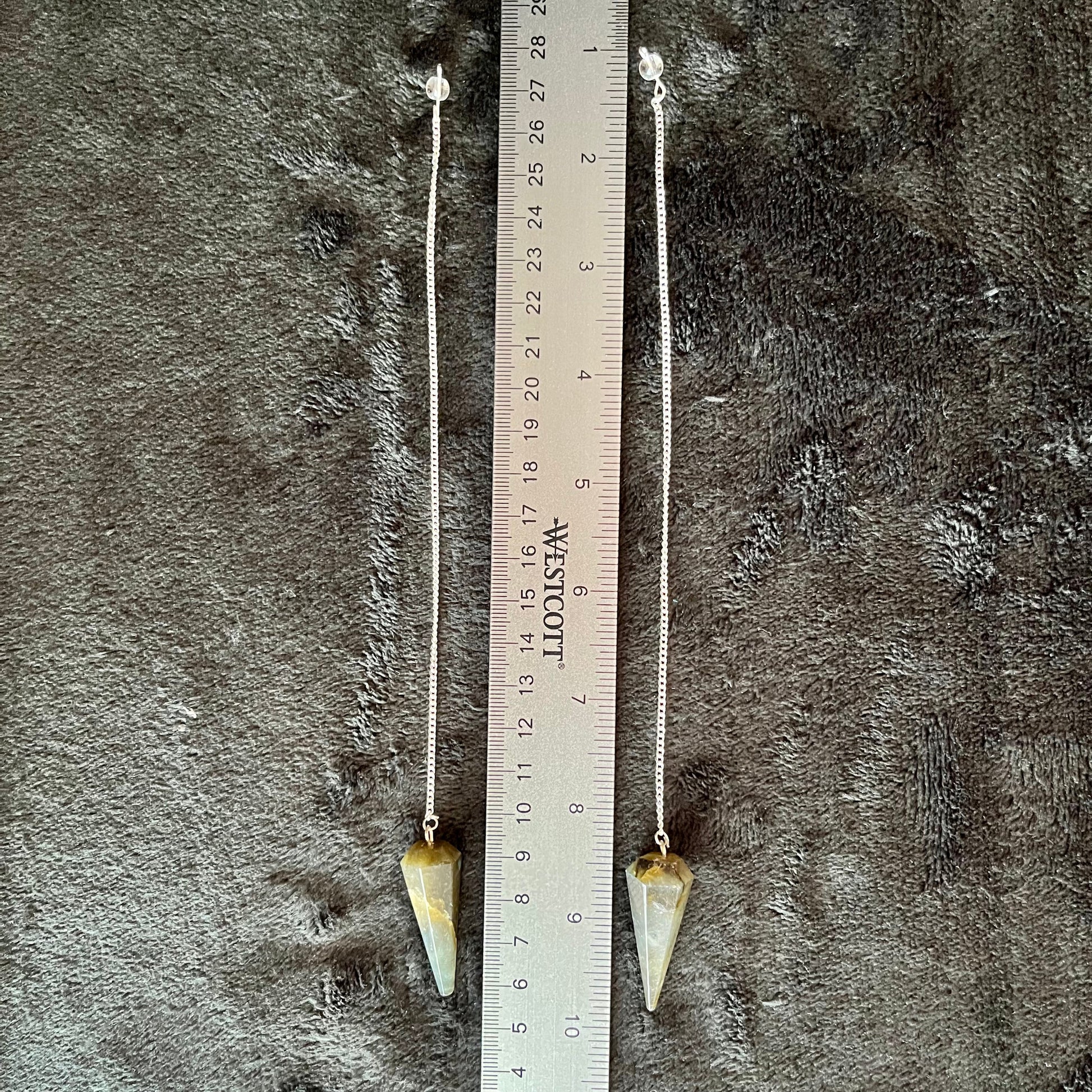 1 1/2 inch Labradorite crystal point pendulum attatched to an 8 inch silve chain, displayed next to a ruler to show size