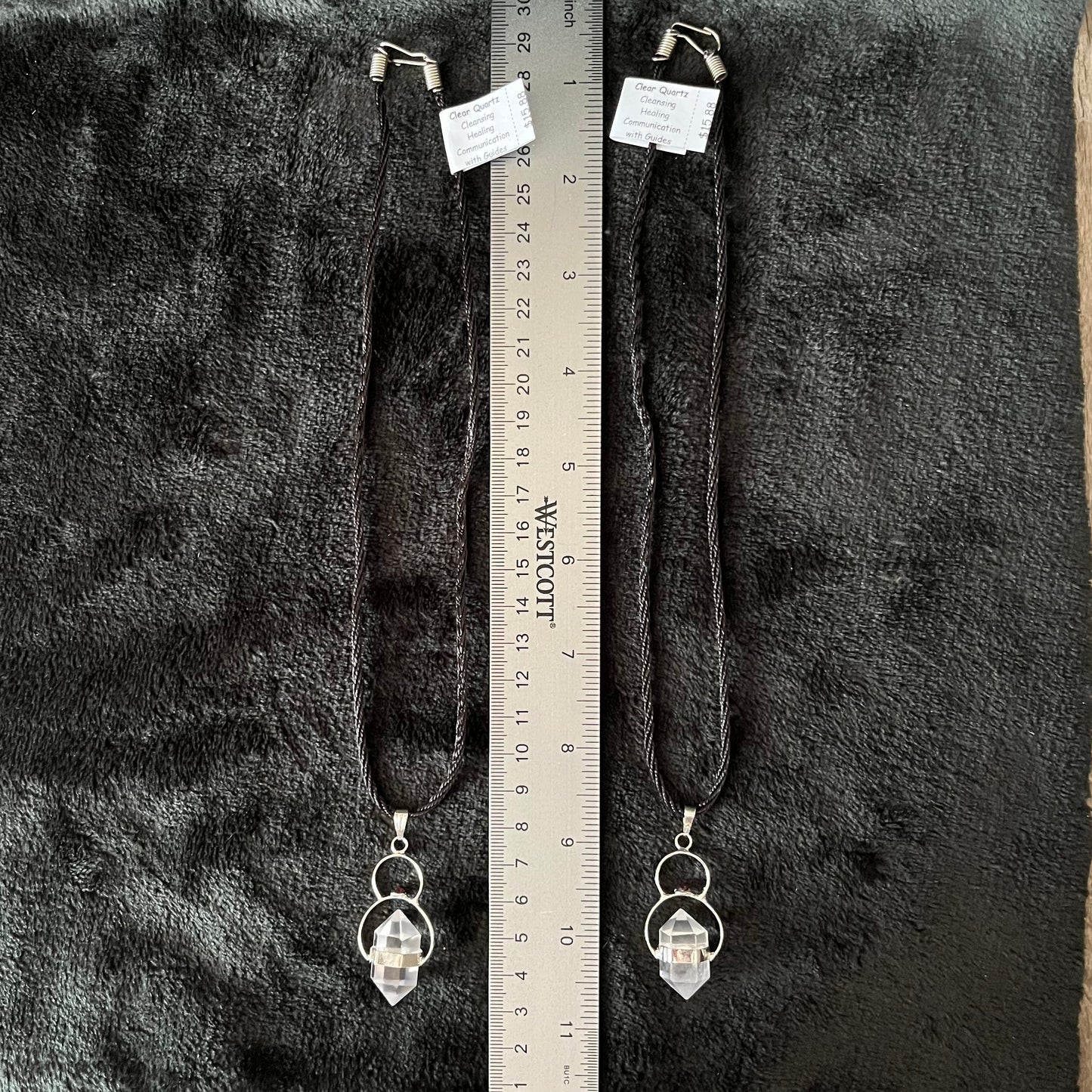 2 Clear quartz double point crystal necklaces displayed next to a ruler to show size. Pendant is approximately 2” long and cord is 18”
