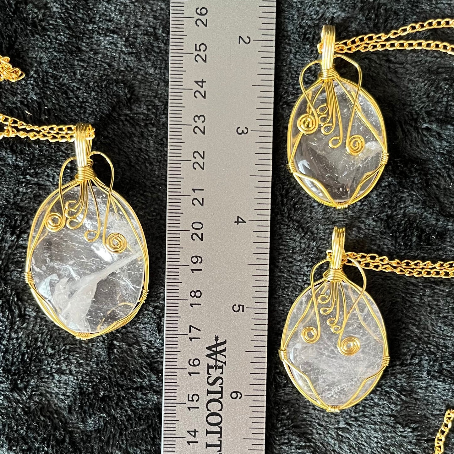 Three gold fancy wire wrapped clear quartz oval stone pendants attatched to a gold tone chains. quartz stones range between 1 1/4" - 1 1/2" long.