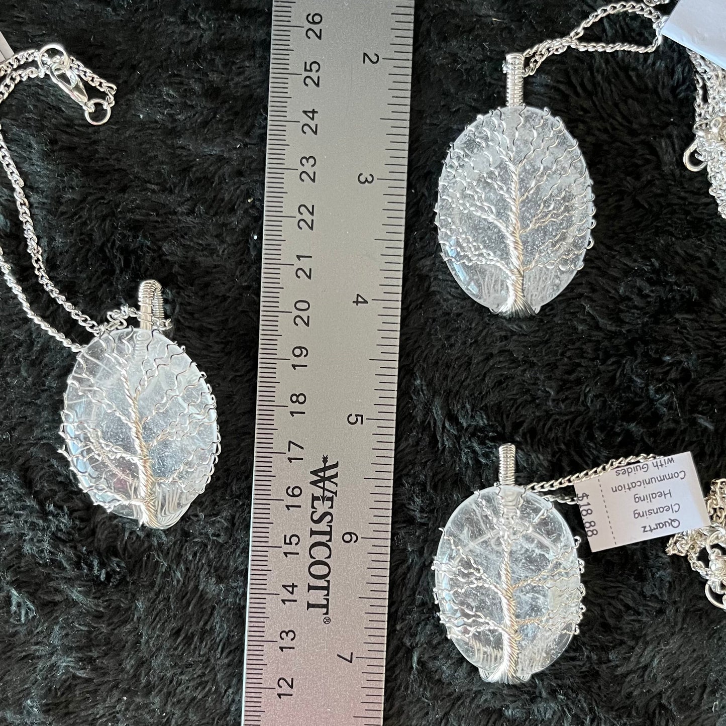 Fancy wrap, tree of life wire wrapped dazzling clear wuartz oval pendant attatched to a silver chain, displayed next to a ruler. pendant is approximately 2 inches long