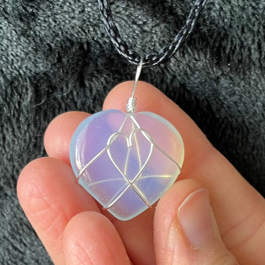 silver wire wrapped transluscent white opalite heart pendant, approximately 1" long, attatched at a black cord. 