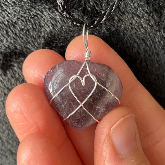 close up of 1 inch purple and white amethyst heart, silver wire wrapped pnedant attached to a black cord