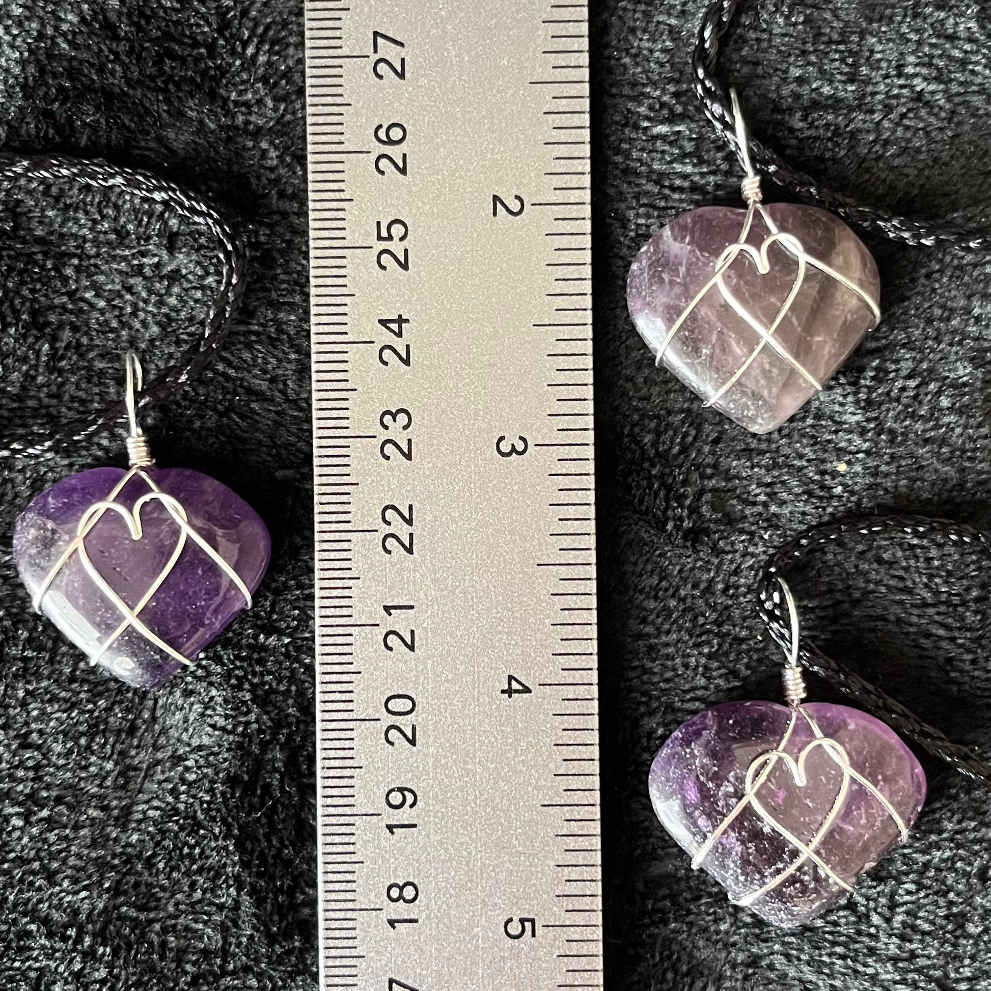 close up of 1 inch purple and white amethyst heart, silver wire wrapped pnedant attached to a black cord, displayed next to a ruler
