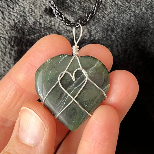 Silver wire wrapped green jade heart pendant, approximately 1" X 1", attached to a black cord