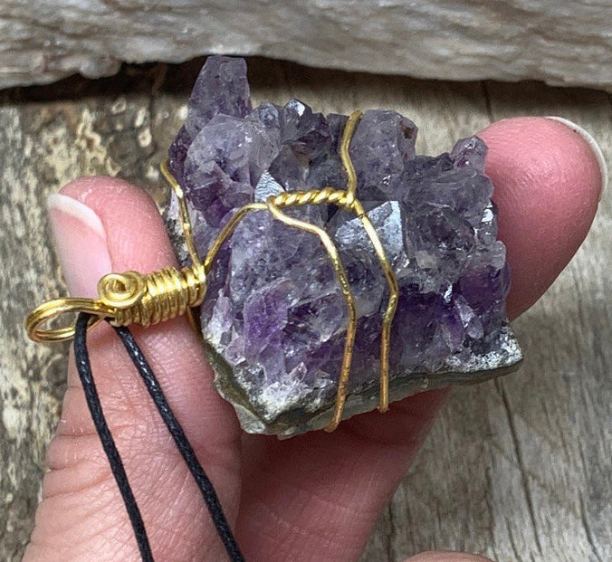 Wire-wrapped necklace adorned with a small amethyst cluster, beautifully showcasing the natural crystal formations, elegantly combining earthy charm with artistic craftsmanship."