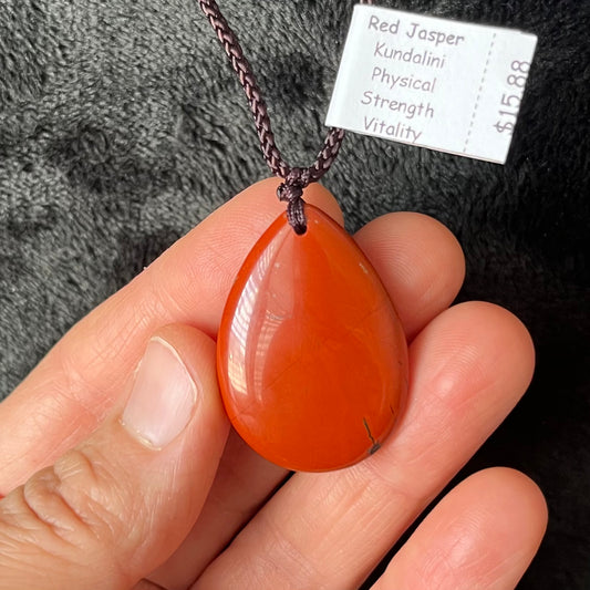 Striking red Jasper tear drop pendant necklace, featuring a rich, earthy red gemstone suspended from a an adjustable black cord adding warmth and natural beauty to your jewelry collection."