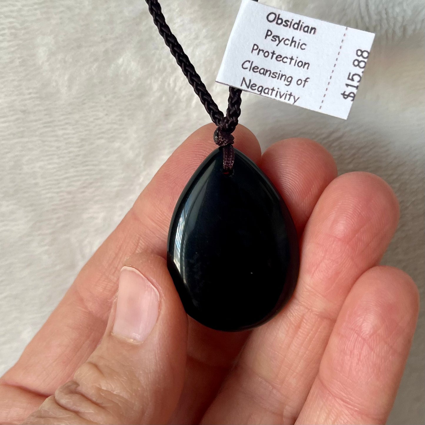 Sleek obsidian teardrop pendant necklace, showcasing the beauty of black volcanic glass in a refined design, suspended from a delicates adjustable black cord for a touch of modern sophistication.