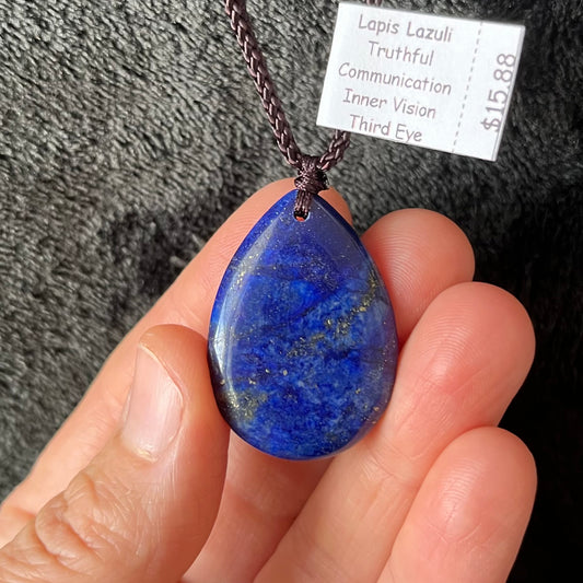Exquisite lapis lazuli tear drop pendant necklace, featuring a deep blue gemstone with grey streaks suspended delicately from an adjustable brown cord, adding elegance to any ensemble."