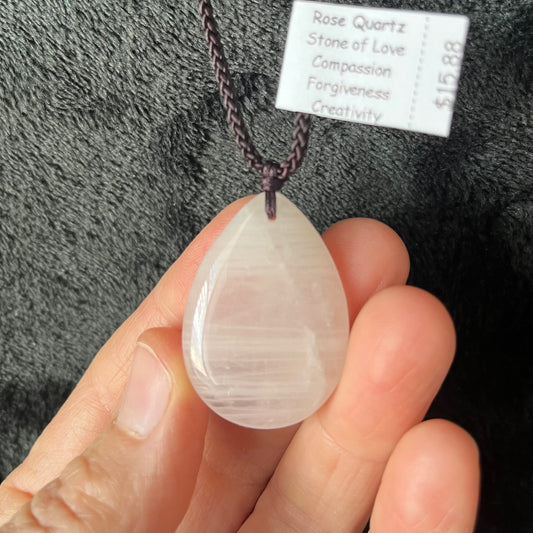 "Elegant rose quartz teardrop pendant necklace, featuring a delicate pink crystal suspended gracefully from a delicate adjustable brown cord, exuding a timeless and romantic allure."