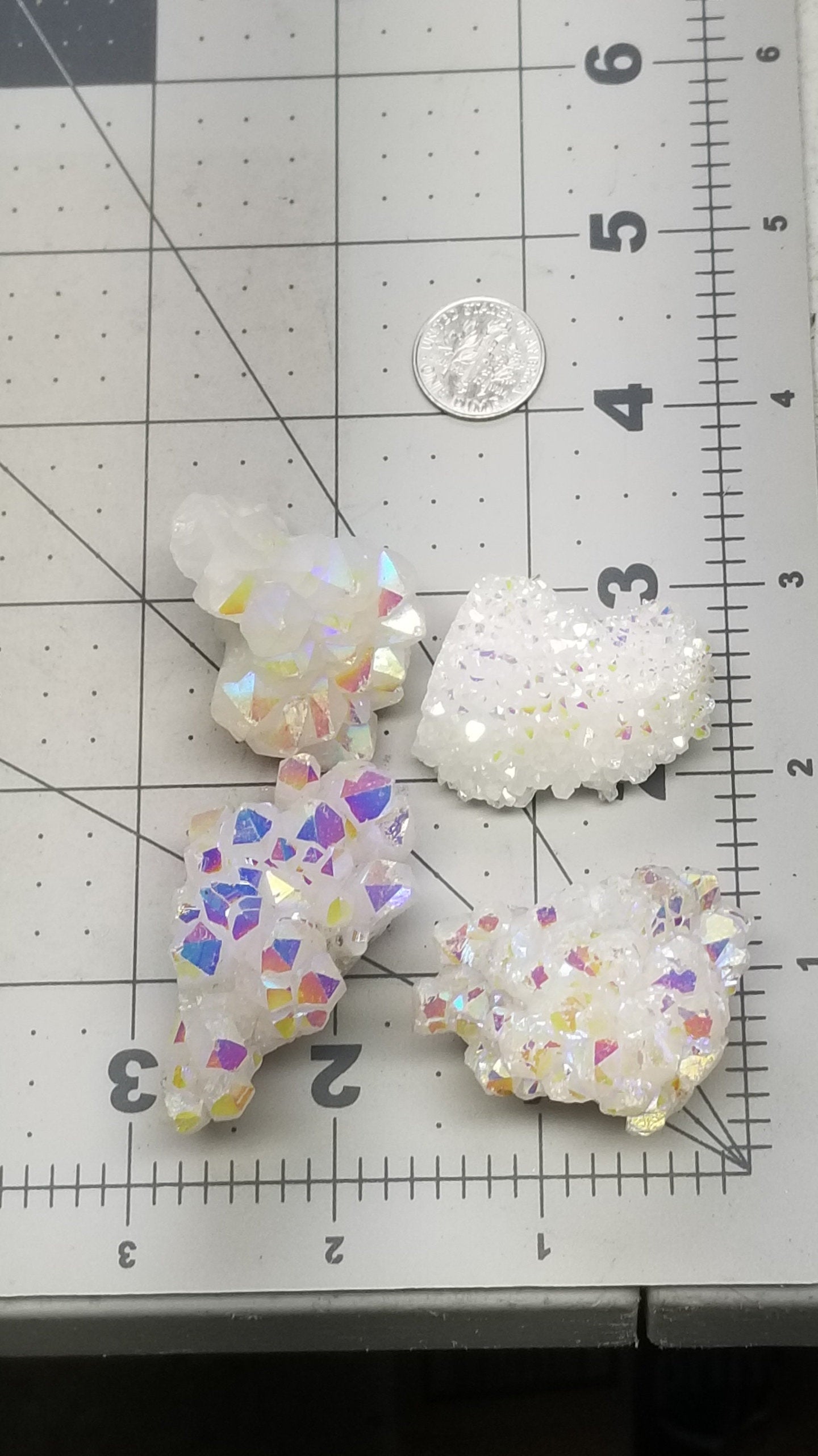 For glistening, iridescent angel aura, quartz clusters displayed next to a ruler. Clusters are 1 1/2 inches to 2 inches in size.