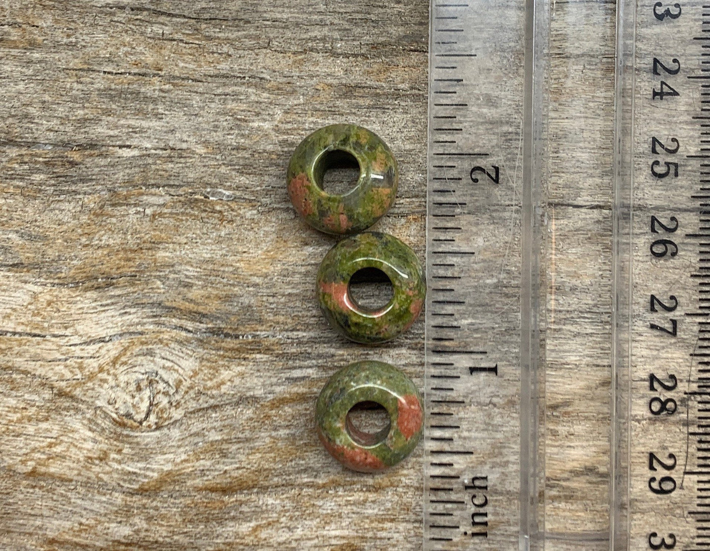 Unakite Jasper beads featuring earthy green and peach tones, next to a ruler
