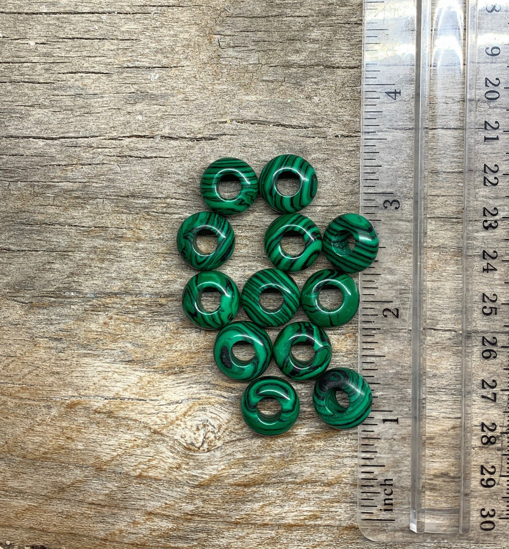 "Close-up of vibrant green malachite beads with unique striated patterns, creating an eye-catching accessory, positioned next to a ruler.