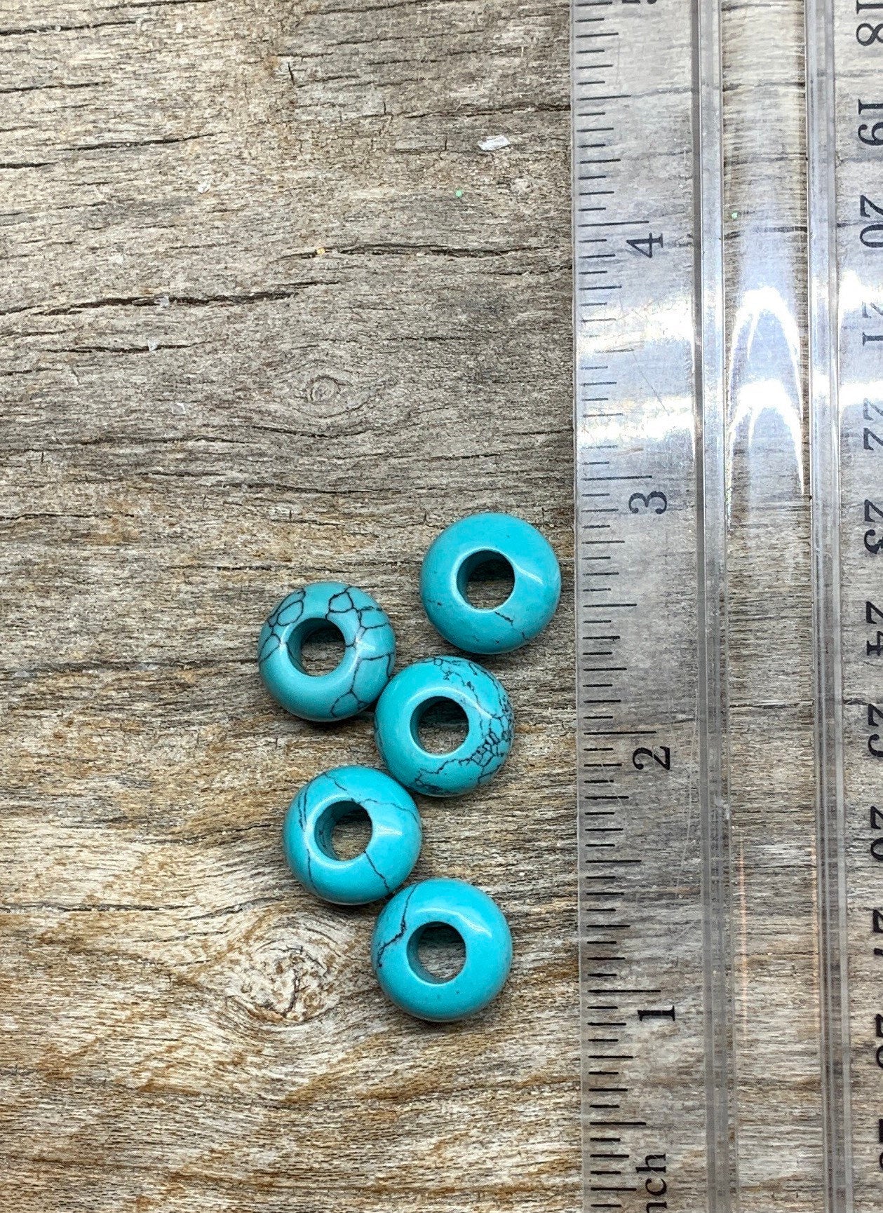 "Close-up of 14mm blue howlite crystal beads, showcasing their vibrant blue color and unique marbled patterns, positioned next to a ruler to show size