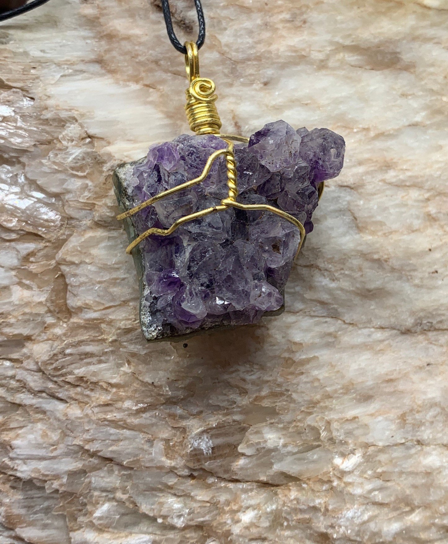 Gold wire wrapped amethyst, cluster pendant, approximately 1 1/4” long, attached to an adjustable black cord ￼