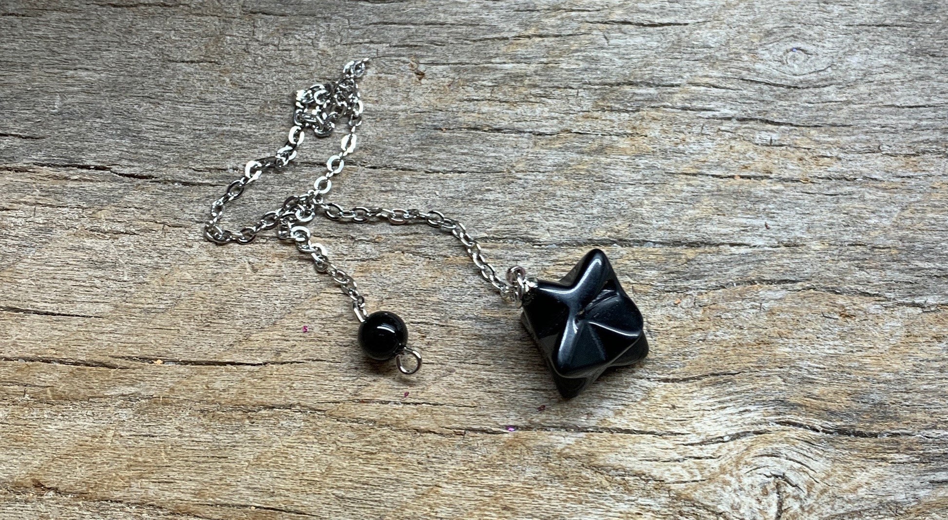 3/4 inch black obsidian merkaba pe lndukim attetched to a silver 8 inch chain.