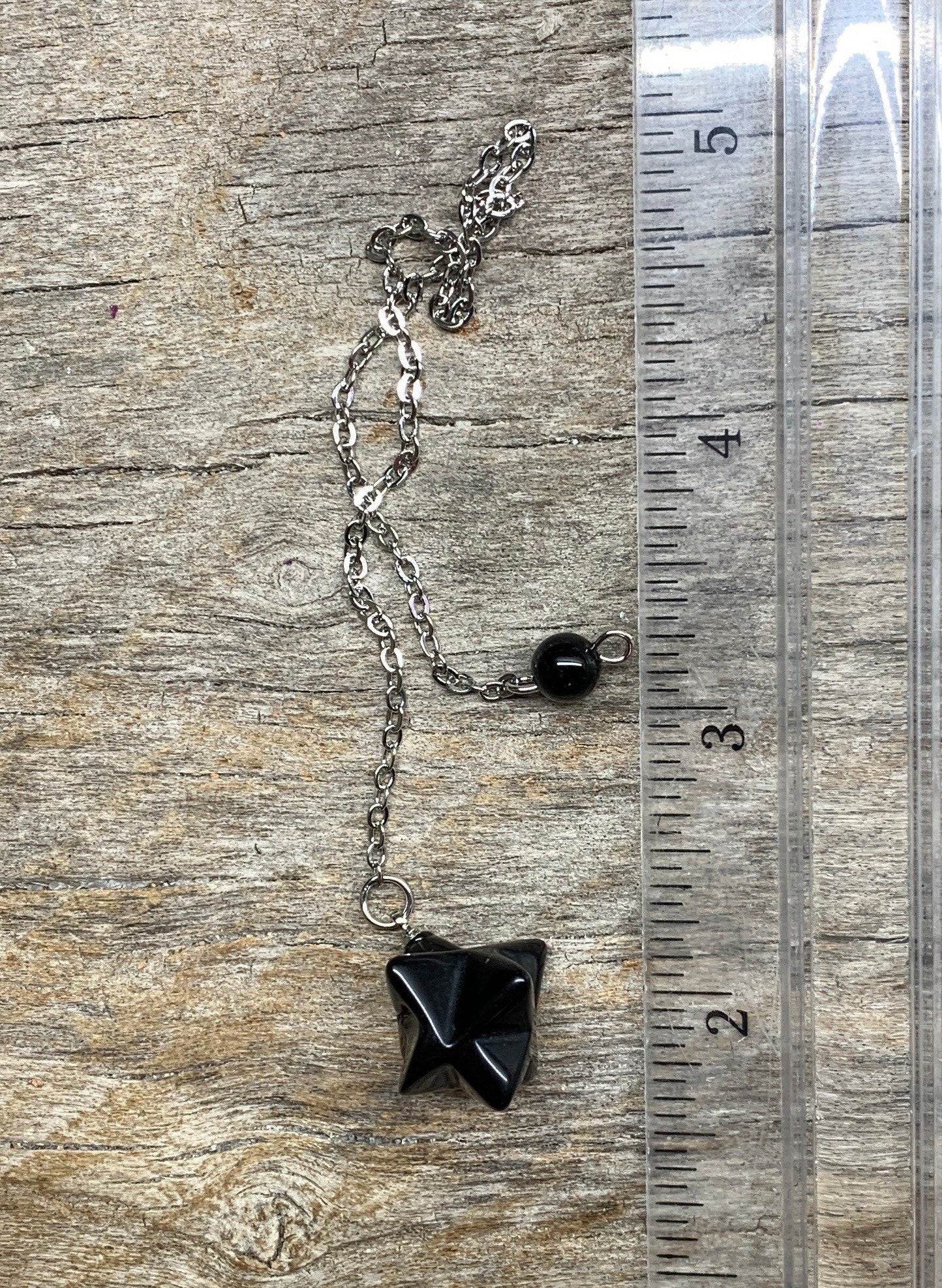 black obsidian 3/4 inch merkaba pendulum attatched to a silver 8 imch chain.