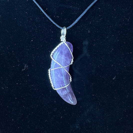 amethyst crescent moon, silver wire wrapped pendant attatched to a black adjustable cord displayed against a black background to enhance the beautiful purple tone interlaced with white 