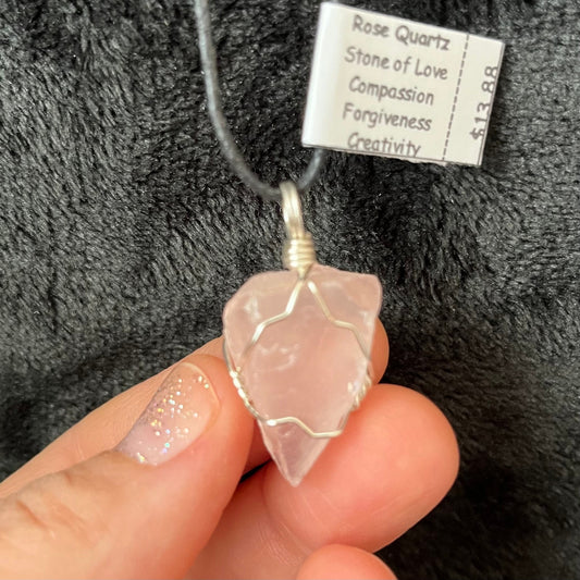 "Handcrafted wire-wrapped rose quartz necklace featuring a polished crystal ntricately woven with silver wire and artatched to an adjustable black cord