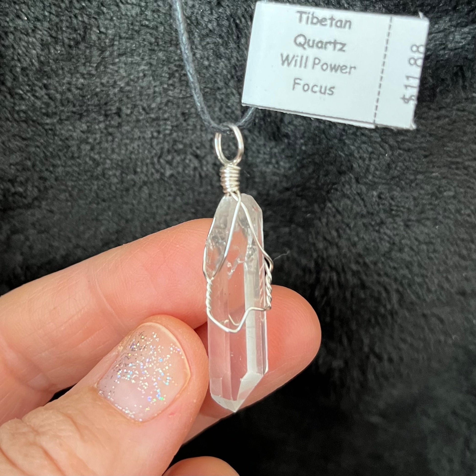 “Alt text: A handmade necklace crafted from Tibetan quartz crystal, featuring a wire-wrapped pendant with intricate silver wirework. The clear quartz stone is prominently displayed, capturing light and radiating a subtle glow. The necklace is elegantly designed, showcasing the natural beauty of the crystal and the craftsmanship of the wire wrapping.”