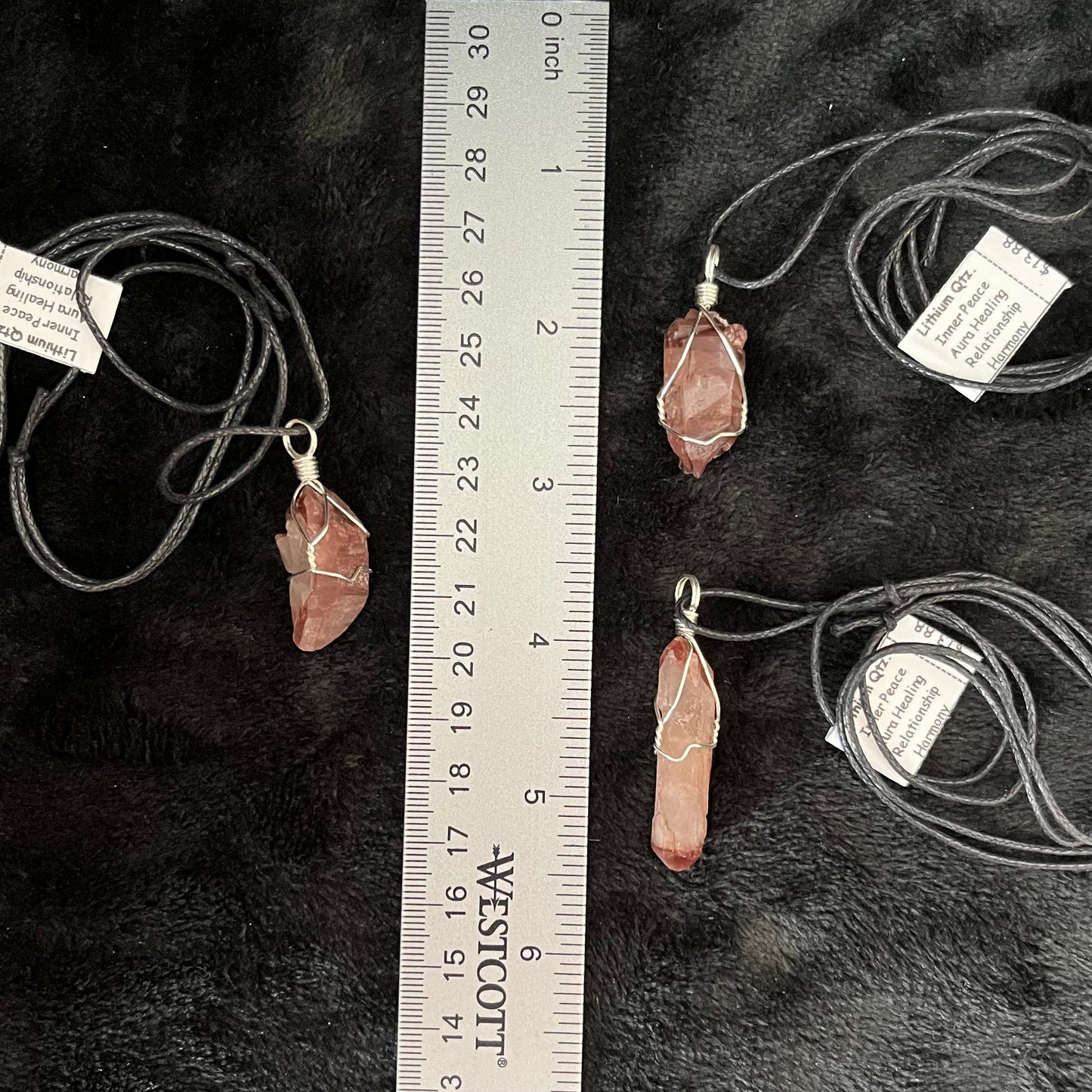 3 silver wire wrapped Lithium quartz point pendants with adjustable black cords, transluscent red orange im color, displayed next to a ruler.  the quartz crystals range in size from 1" to 1 1/2"