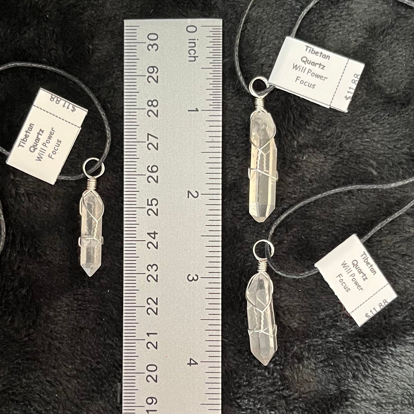 3 handmade ornately silver wire wrapped tibetan quartz crystal pendants, attatched to adjistable black cords, displayed next to a ruler to show size.  The quartz crystals are approximately 1" - 1 1/4" in length.