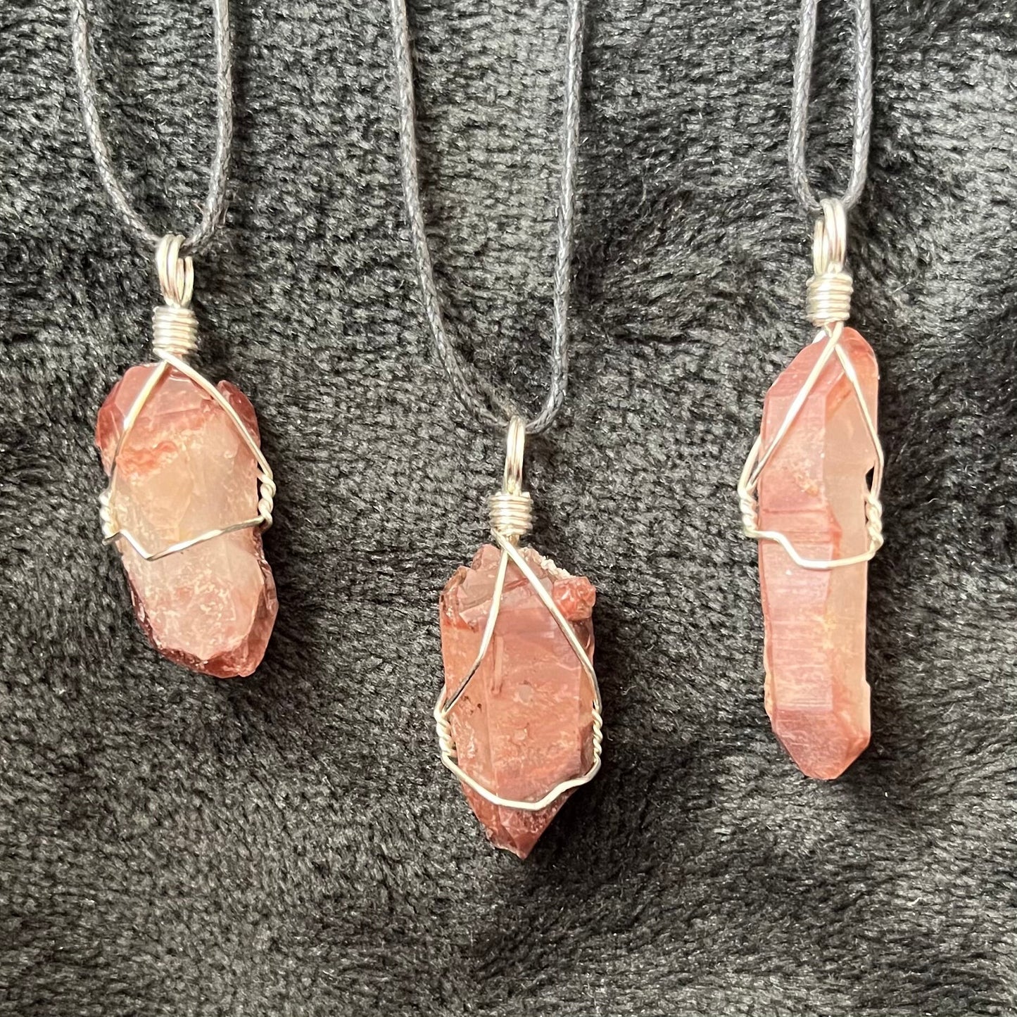 3 silver wire wrapped Lithium quartz point pendants with adjustable black cords, transluscent red orange.