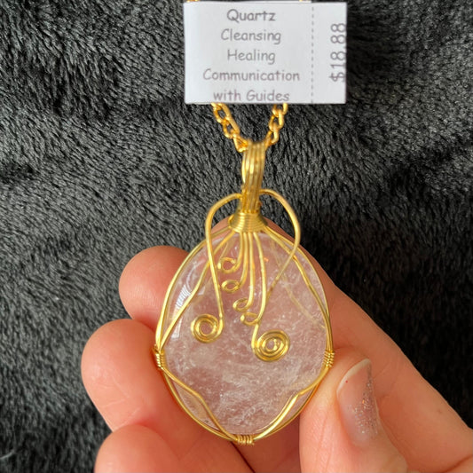 gold fancy wire wrapped clear quartz oval stone pendant attatched to a gold tone chain.