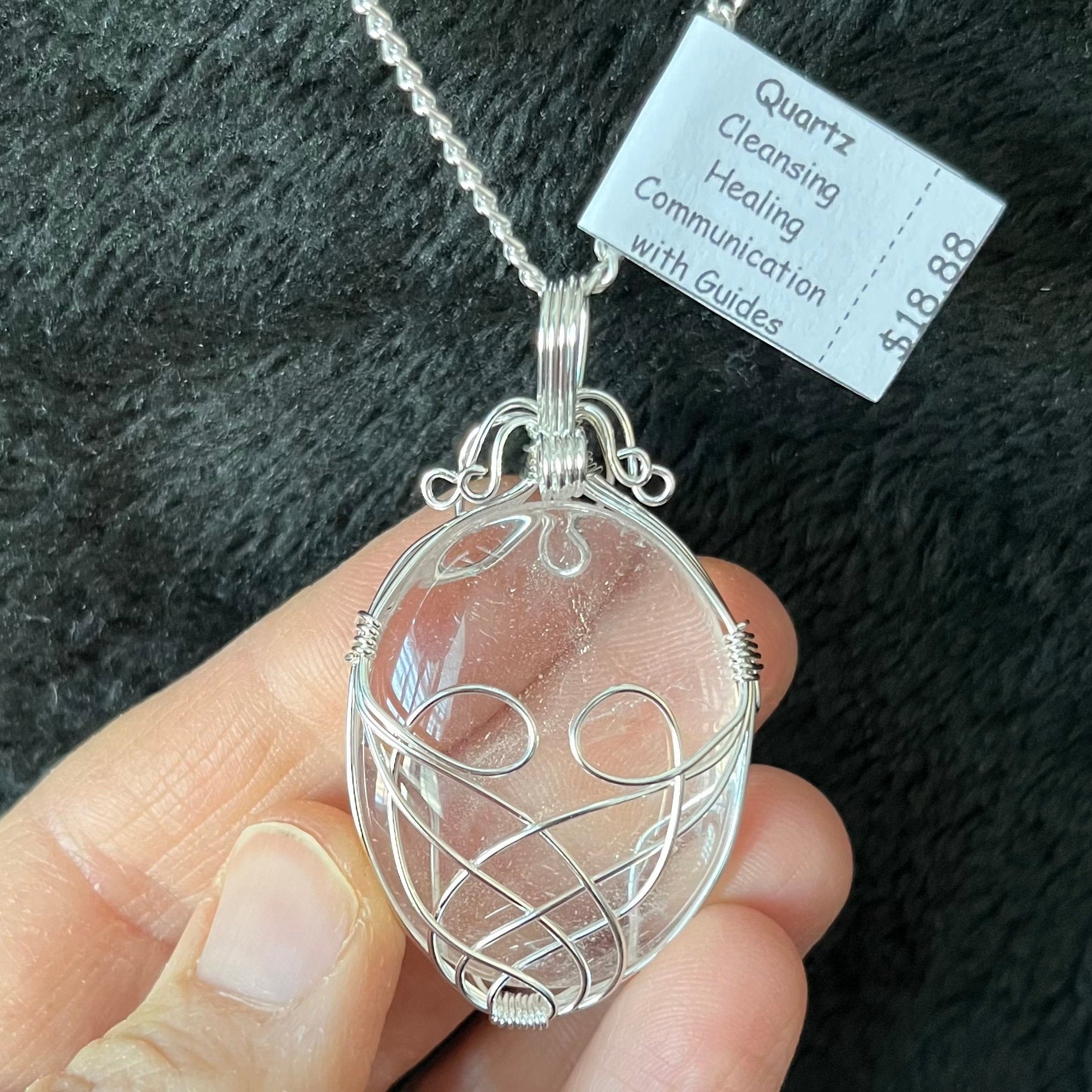 Silver fancy wire wrapped clear quartz oval stone pendant attatched to a silver chain.