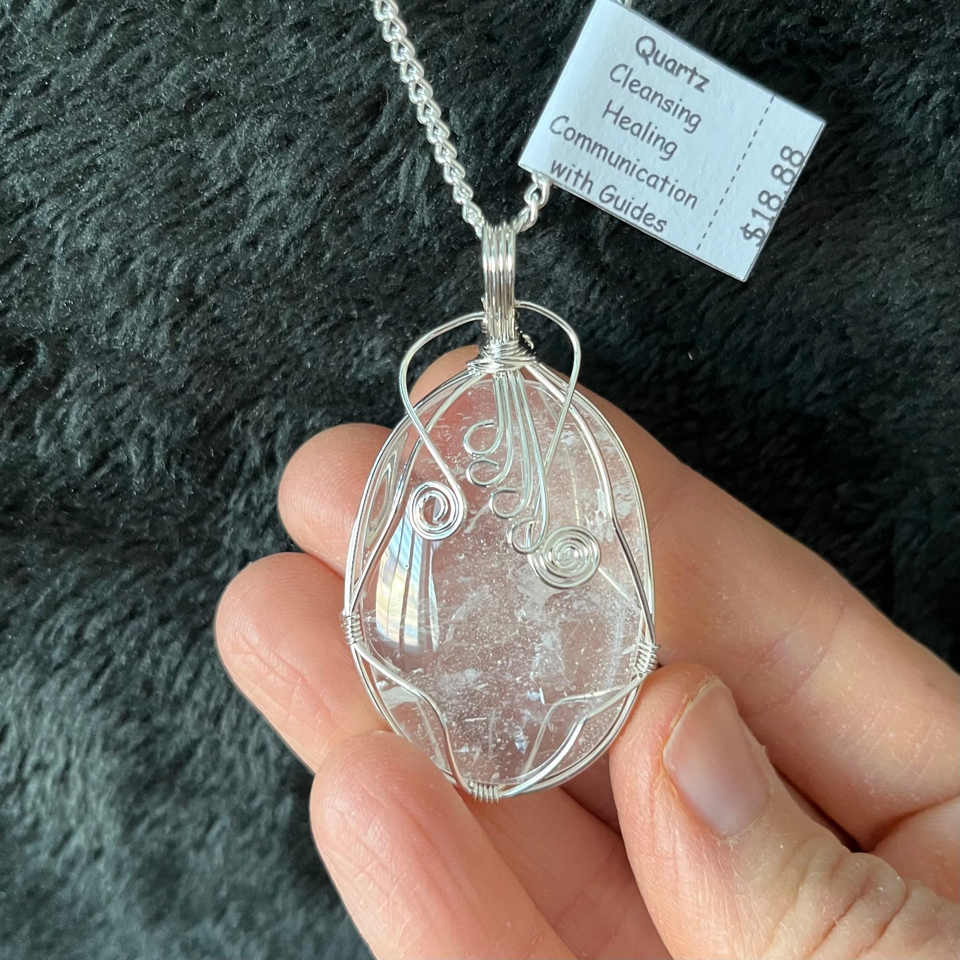 Silver fancy wire wrapped clear quartz oval stone pendant attatched to a silver chain.