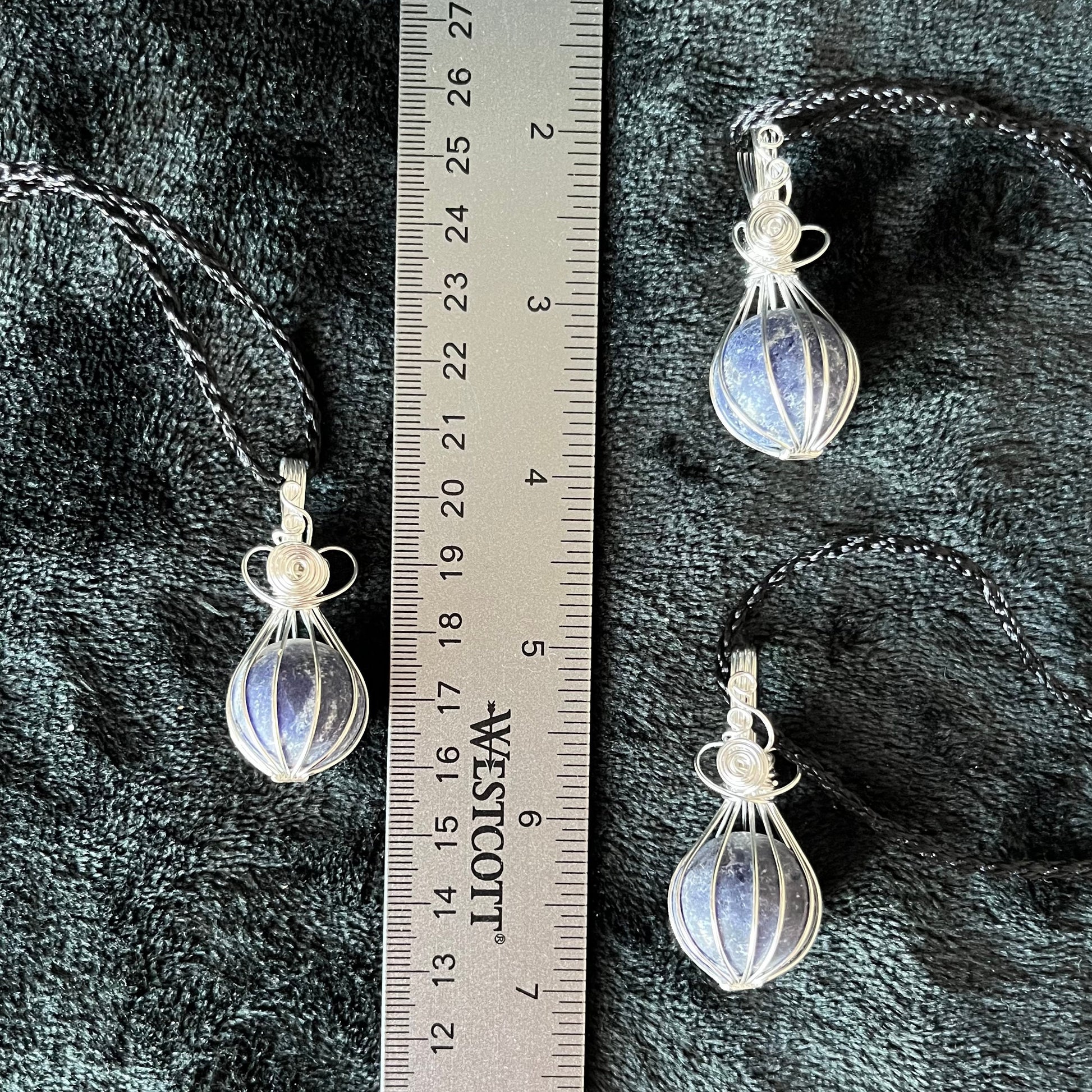 Ornately silver wire wrapped basket pendants containing a blue amd grey sodalite sphere approximately 1/2" -3/4" in diameter amd attatched to black cords