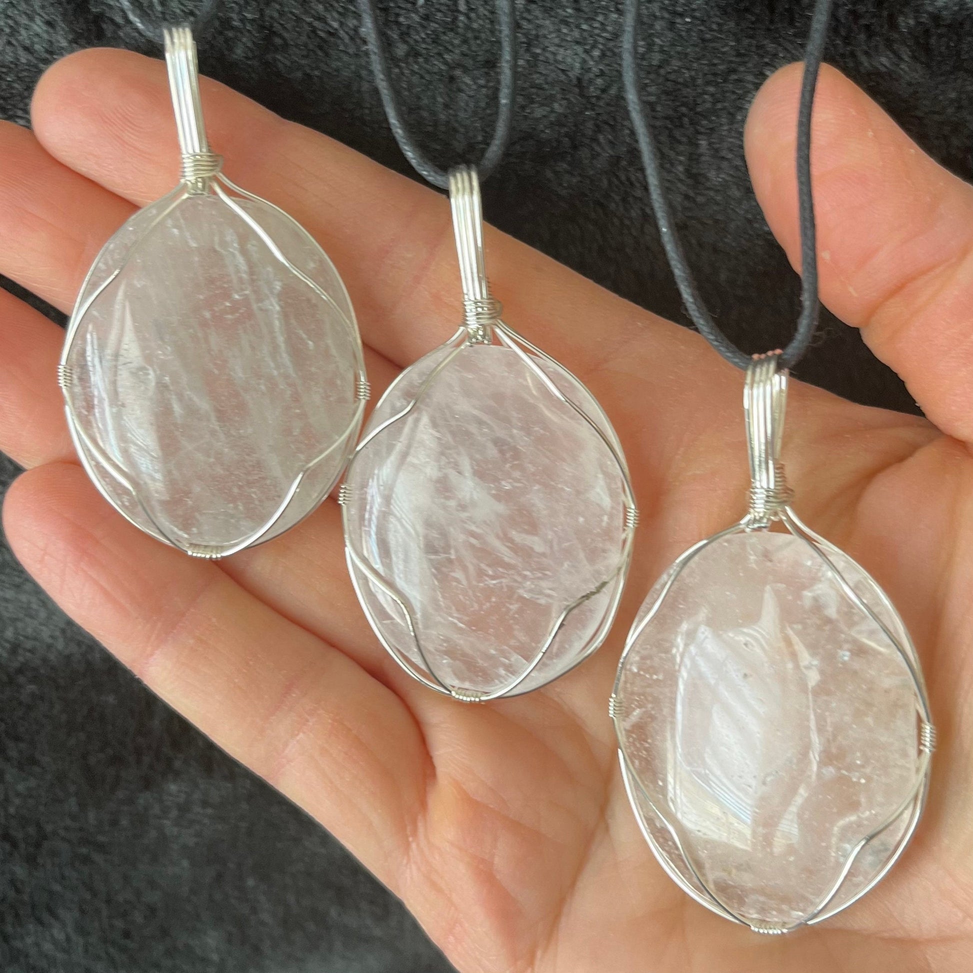3 clear quartz worry stones silver wire wrapped in a way that frames the stones beautifully, allowing access to the smoothe concave side on the back.  pendants are approximately 2 inches long and attatched to adjustable black cords.