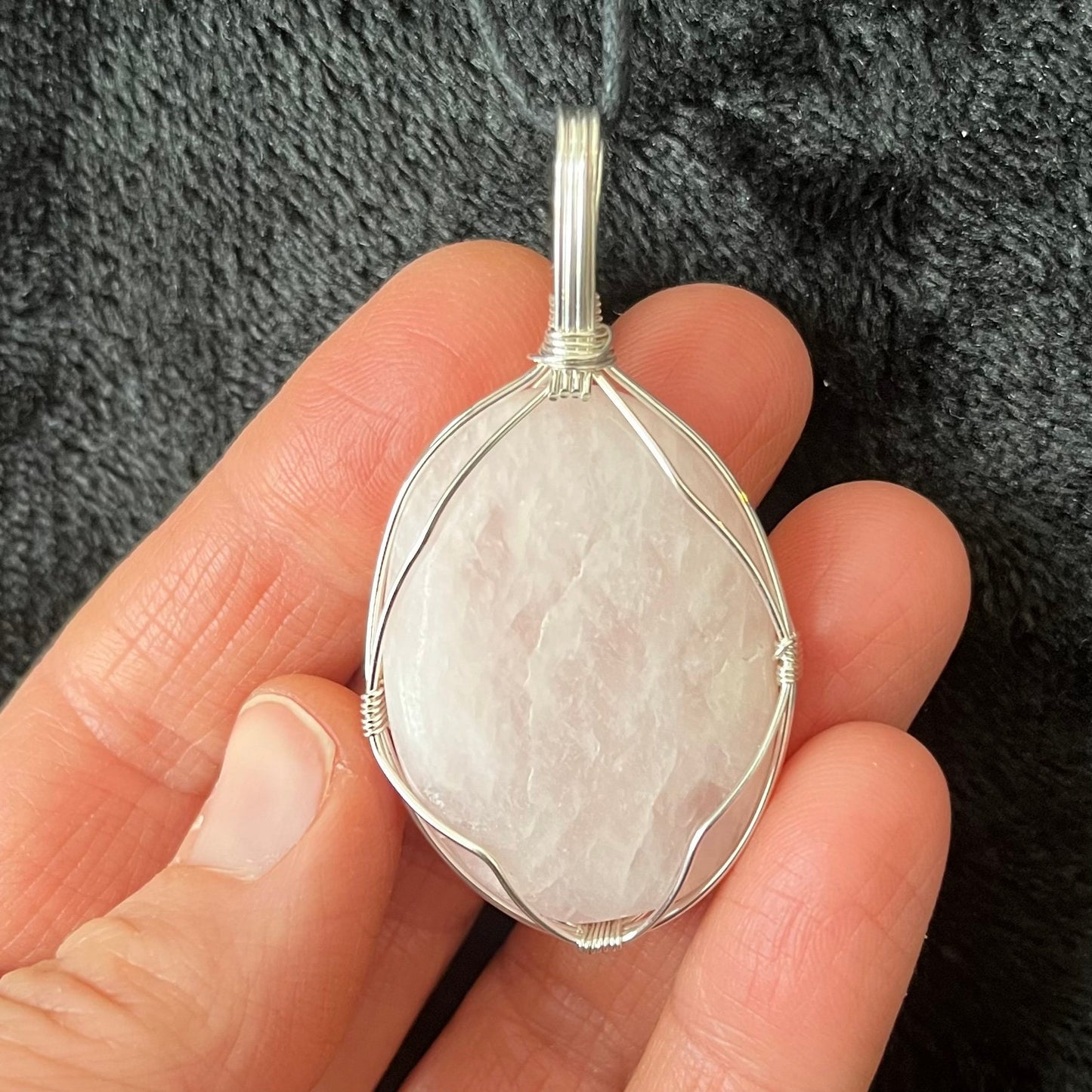  silver wire wrapped with a an or ate and delicate frame, this translucent pink rose quartz worry stone pendant is approximately 1 1/2" long and, attarched to an adjustable black cord.  